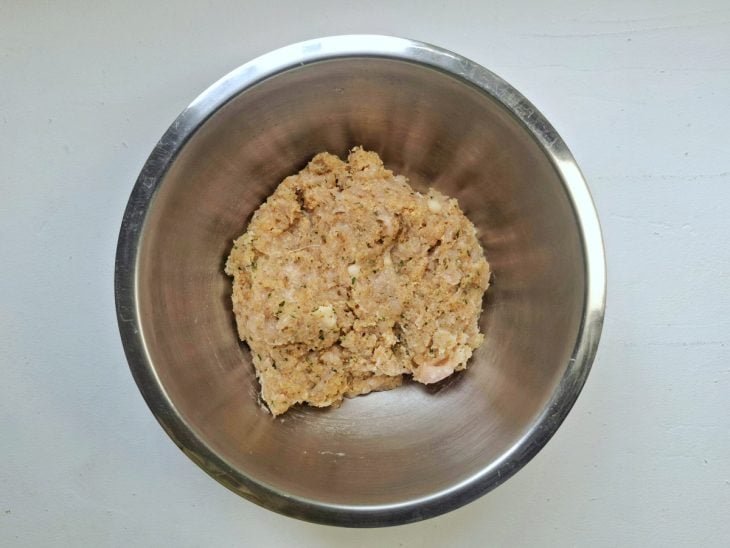 Uma tigela com o frango moído misturado com os outros ingredientes para fazer a massa.