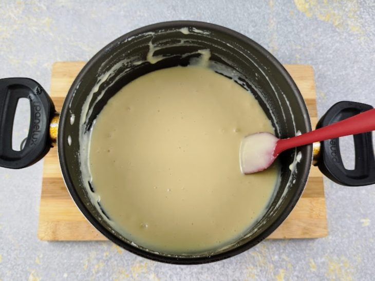 Uma panela com o recheio do rocambole e uma espátula.