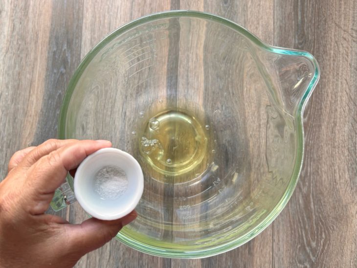 Uma tigela com as claras e sal sendo adicionado.