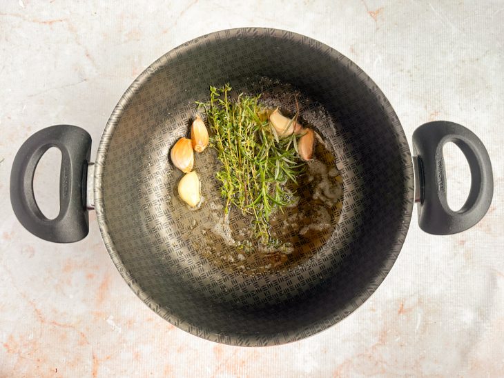 Azeite, alho e as ervas na panela.