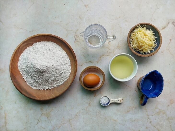 Ingredientes organizados na bancada com queijo ralado e forno já preaquecido.