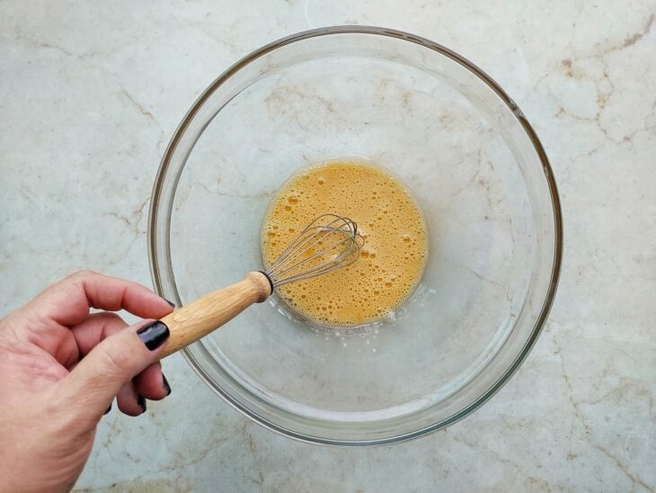 Ovo sendo batido em uma tigela até formar espuma leve.