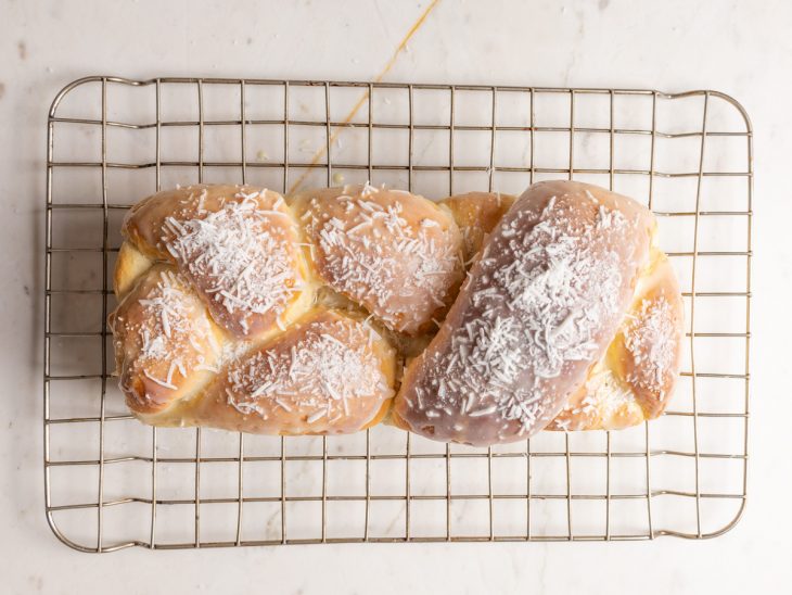 Rosca trançada desenformada sobre uma grade de cozinha.