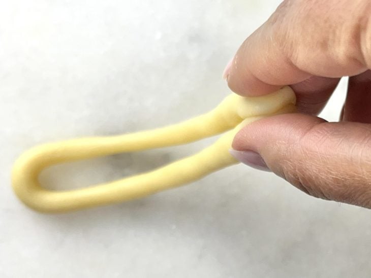Uma tirinha de massa dobrada para formar a rosquinha.