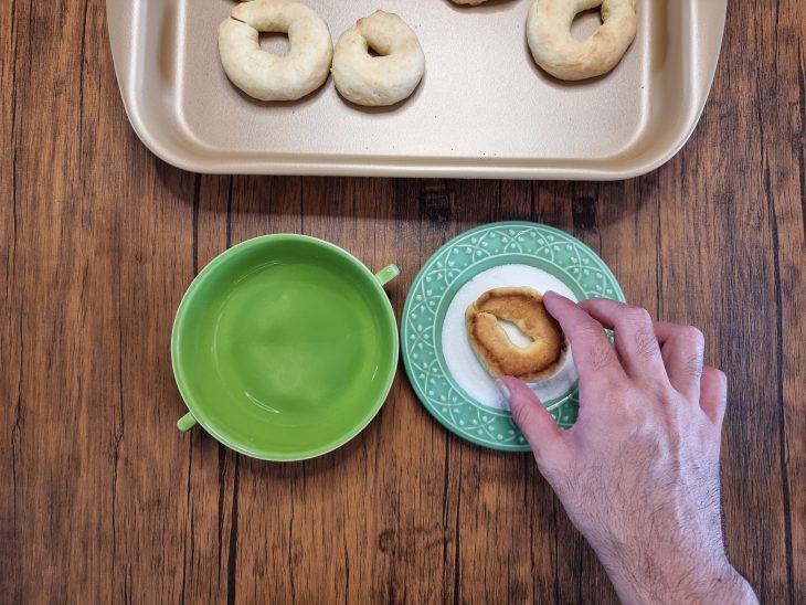 rosquinha de pinga sendo passada no açúcar