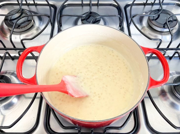 Uma panela ao fogo com sagu, leite condensado e leite de coco.