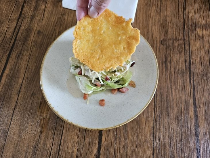 Salada Caesar finalizada com crispy de queijo.