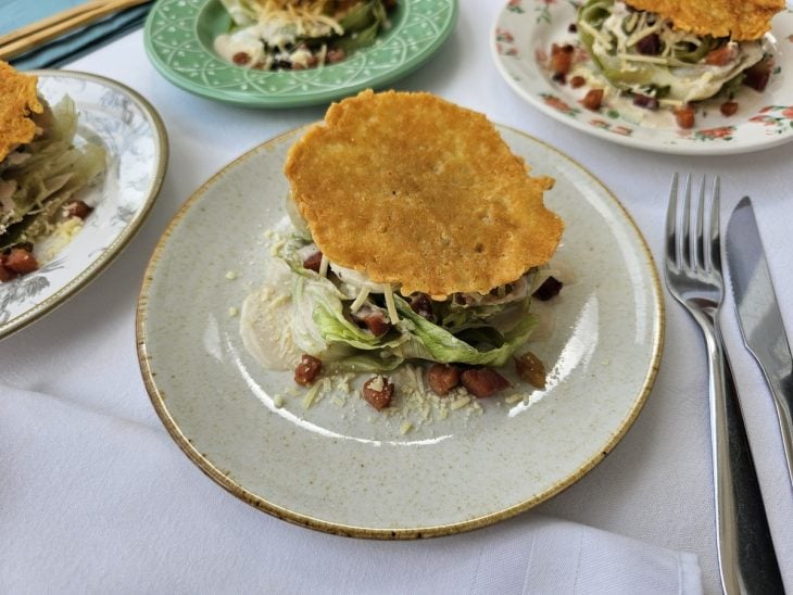 Pratos com saladas Caesar com crispy de queijo montadas.