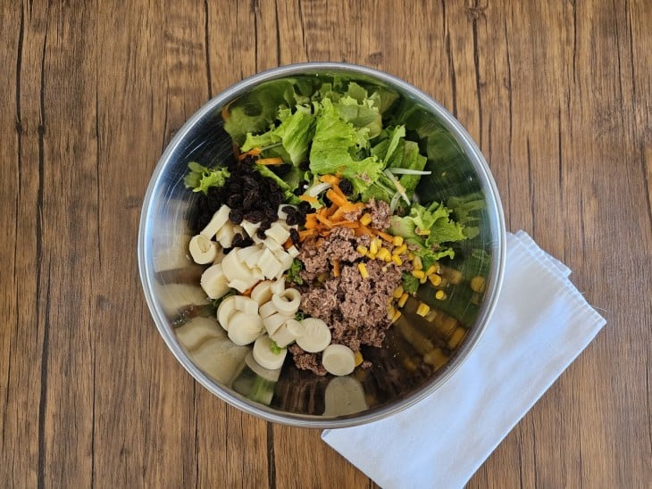 Saladeira com os ingredientes da salada com molho de mostarda e croutons.