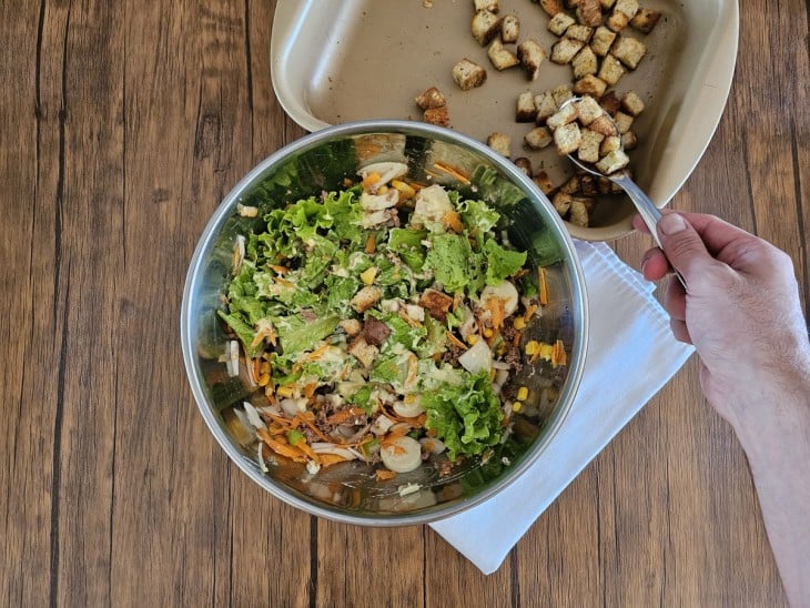 Croutons sendo colocados na salada.