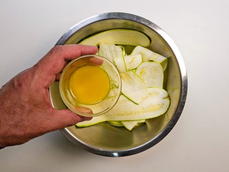 Molho sendo despejado sobre as fatias de abobrinha.