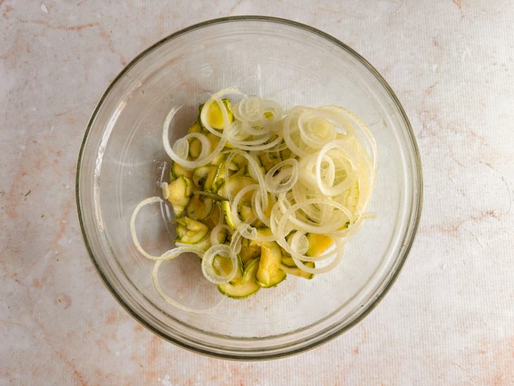 Ingredientes combinados em travessa: abobrinha, cebola, pimenta e cebolinha.