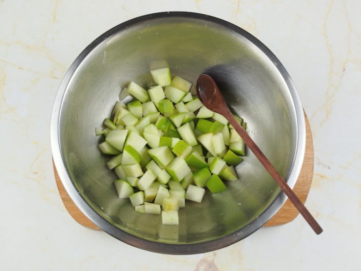 Maçã picada e suco do limão misturados em uma tigela.