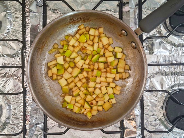 Cubos de maçã sendo adicionados e caramelizados.
