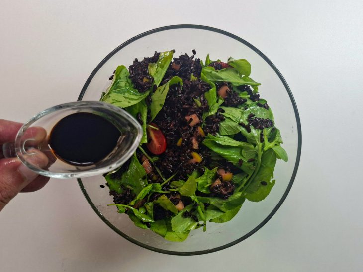 Molho sendo despejado sobre a salada e misturado antes de servir.