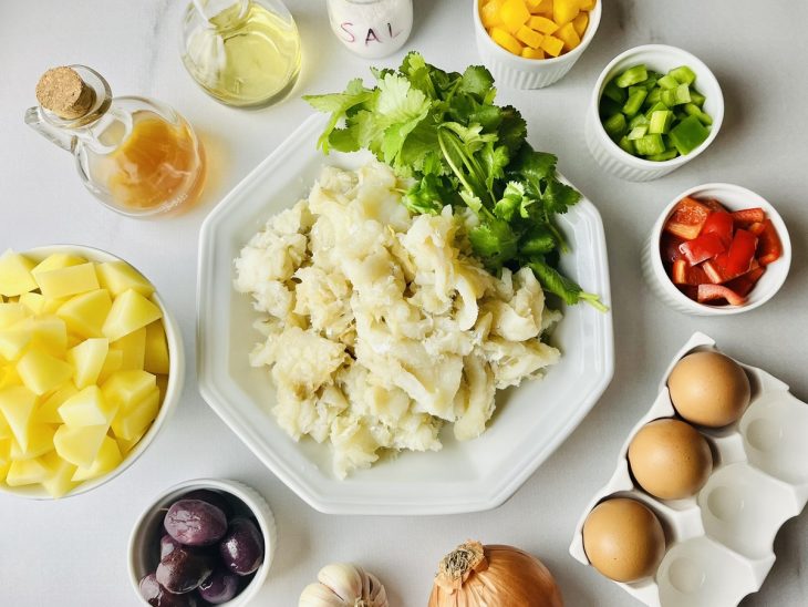 Ingredientes reunidos na bancada com bacalhau já dessalgado.