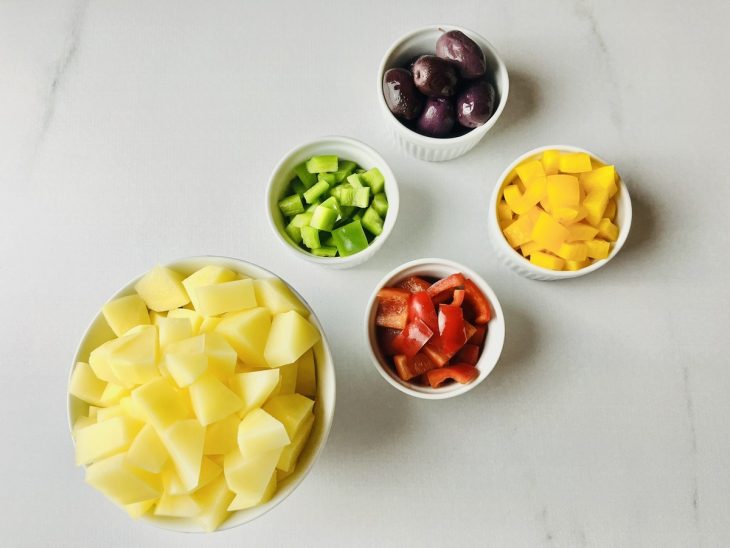 Batatas em cubos, alho ralado, pimentões em tiras e cebola cortada.