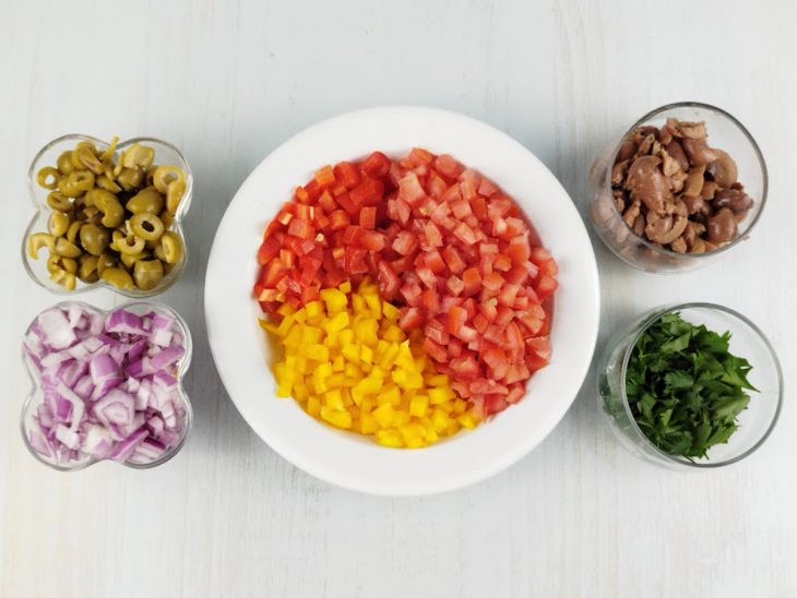 Pimentões, tomates e cebola cortados em cubos, salsinha e azeitonas fatiadas.