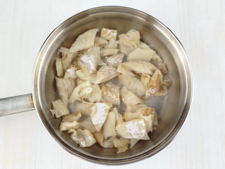 Bacalhau sendo fervido em panela com água.