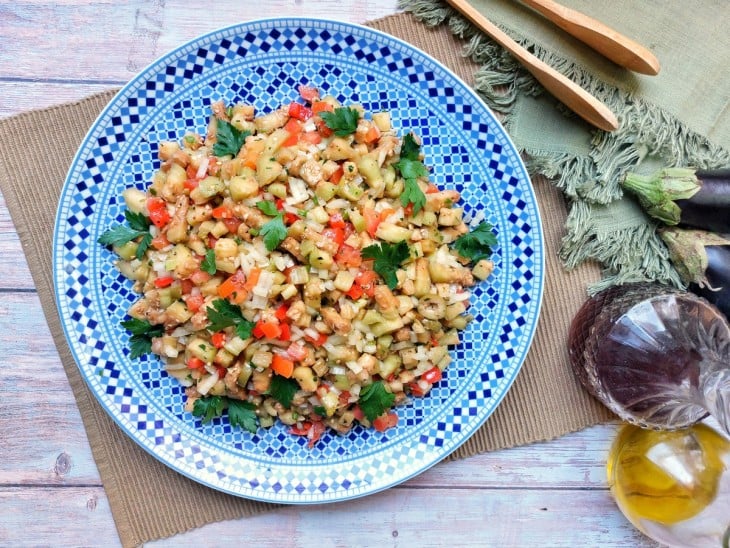 Salada de berinjela crua em um prato azul grande.