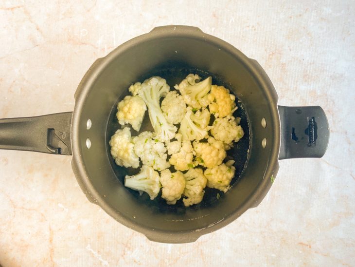 Couve-flor em uma panela de pressão com água, sal e alho.