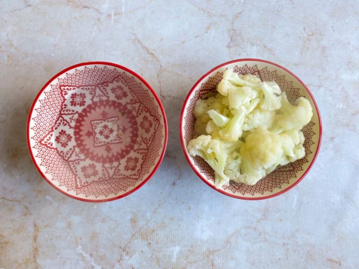 Couve-flor cozida reservada em uma tigela de porcelana pequena.