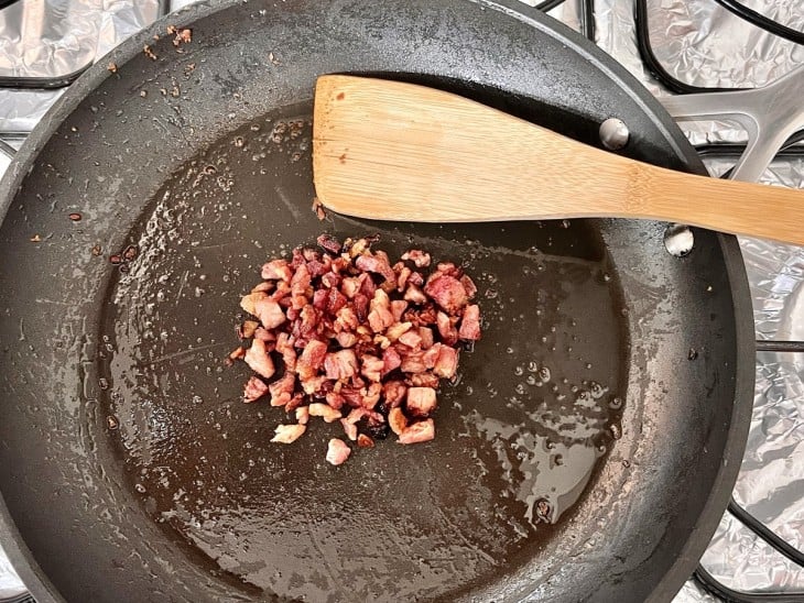 Uma frigideira com bacon picadinho e frito.