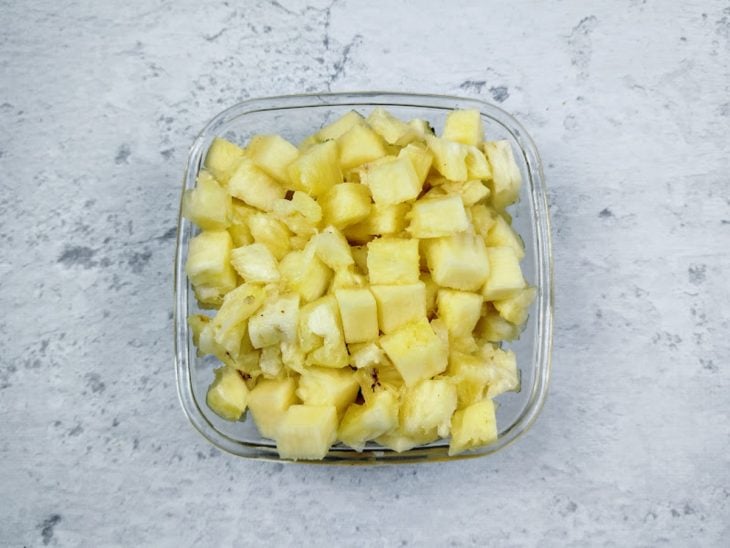 Um recipiente com abacaxi picado.