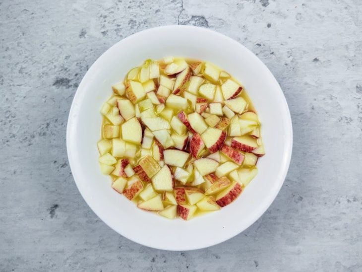 Um recipiente com maçã picada e suco de laranja.