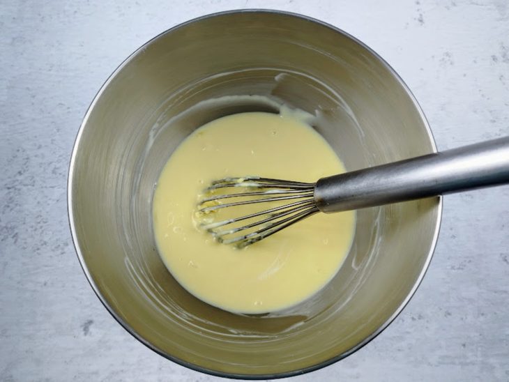 Um fouet e uma tigela com leite condensado, leite Ninho e creme de leite.