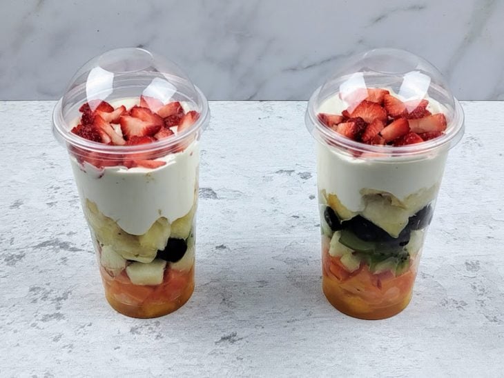 Uma bancada com salada de futas gourmet no pote.