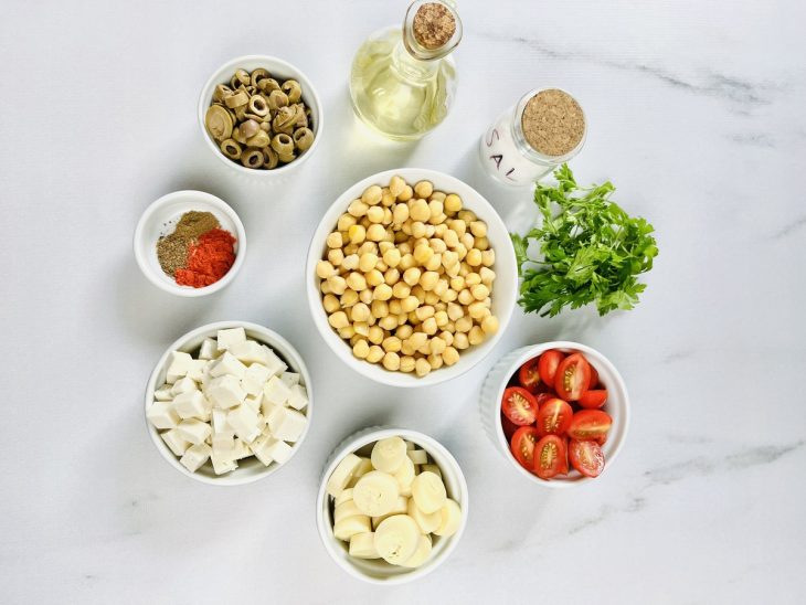Grão-de-bico cru, palmito, ricota e demais ingredientes organizados sobre a bancada.