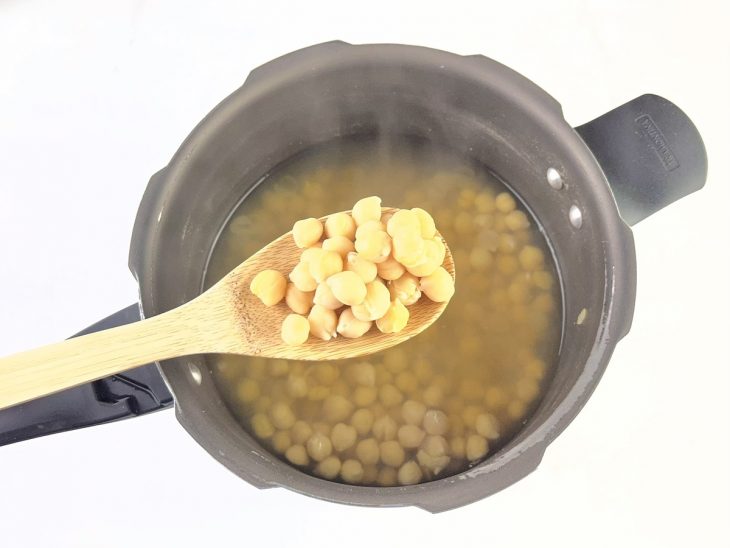 Grão-de-bico sendo cozido em panela com água até ficar macio.