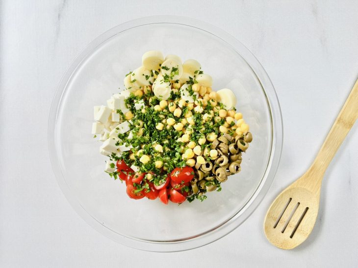 Grão-de-bico cozido em uma tigela com tomatinhos, azeitonas, ricota, palmito e cheiro-verde.