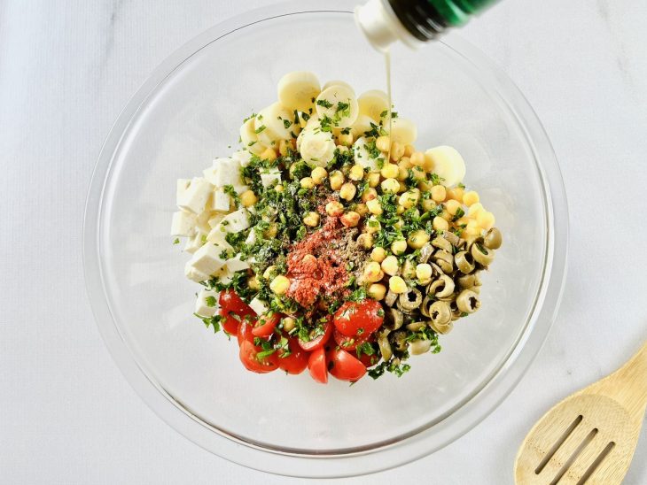 Salada sendo temperada com azeite, sal, pimenta-do-reino e páprica.