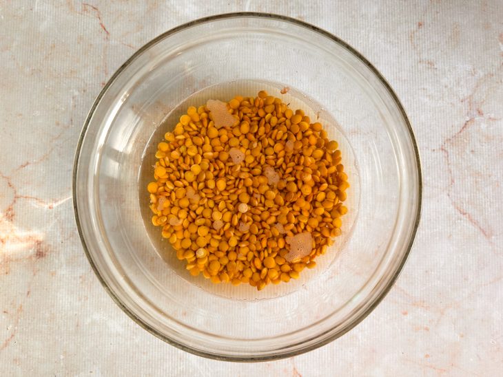 Grãos de lentilha de molho numa tigela redonda de vidro.