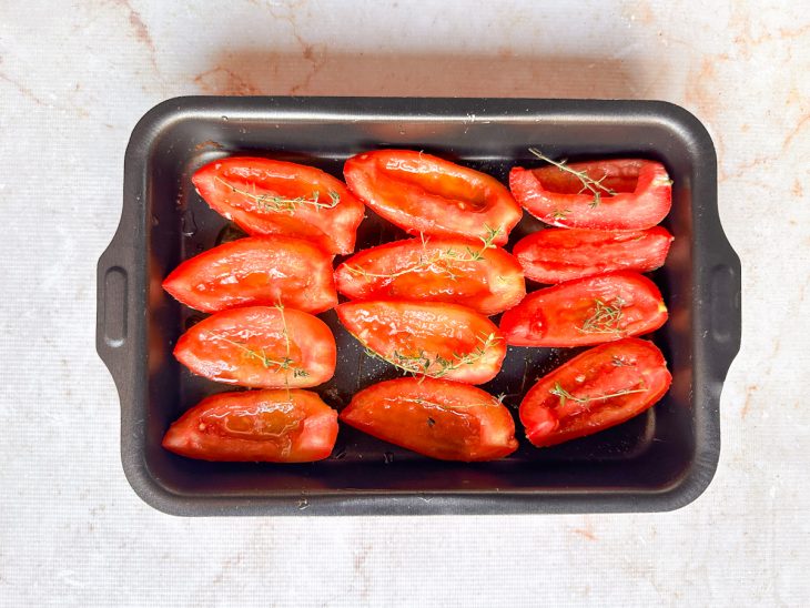 Tomates temperados dispostos numa assadeira.