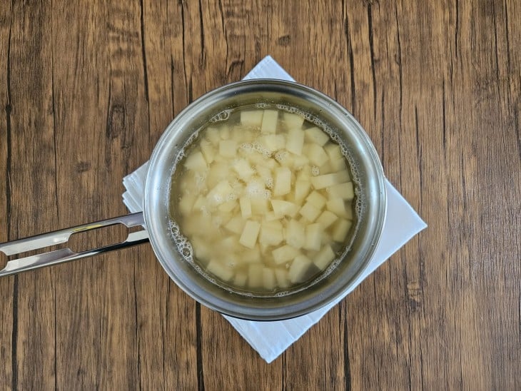 Panela com água e batatas picadas.