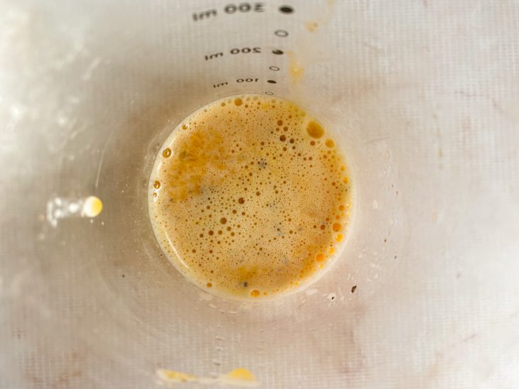 No mixer, a gema crua, os dentes de alho amassados, o suco do limão, o sal e a pimenta-do-reino batidos.
