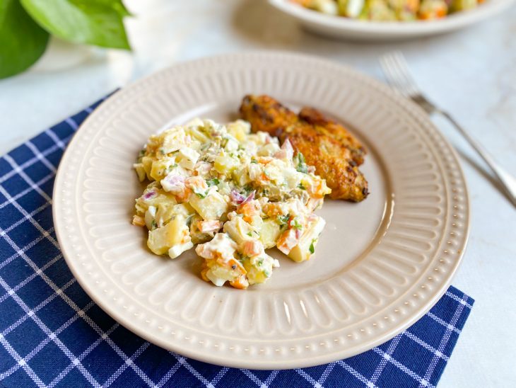 Salada pronta, servida em prato, acompanhando uma tulipa de frango.
