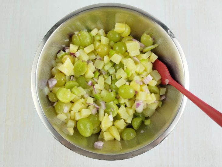 Batatas misturadas com as uvas, salsão e a cebola.