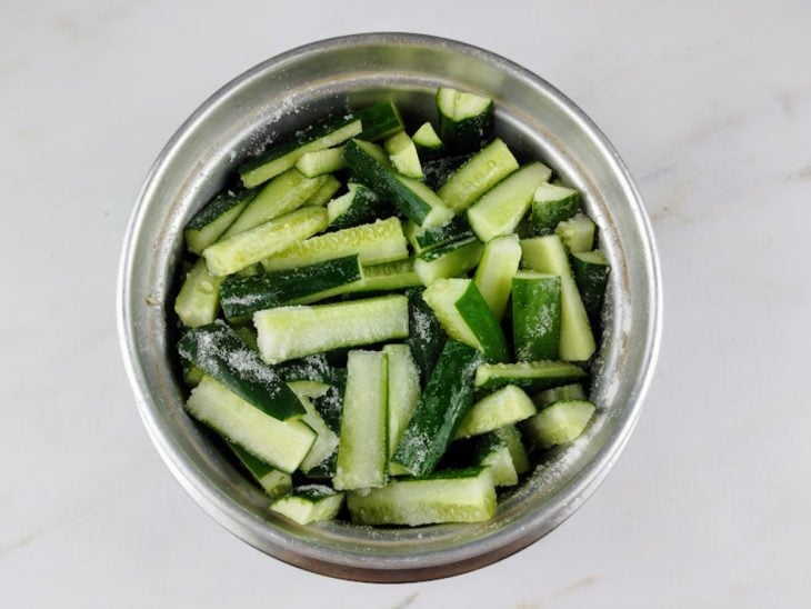 Pepino desidratando com sal em uma tigela de alumínio.
