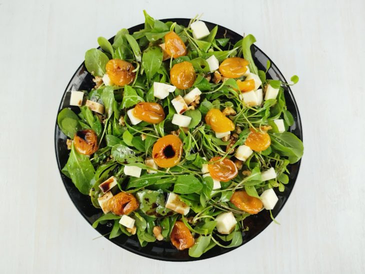 Damascos sendo distribuídos sobre a salada.