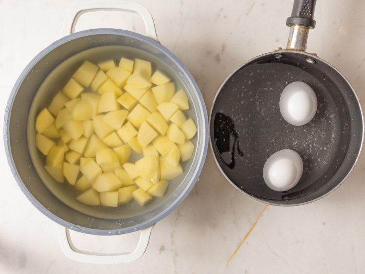 Uma panela com água e batatas, e outra panela com água e ovos.