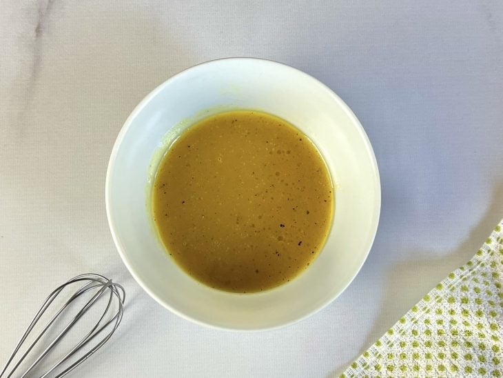 Uma tigela com a mistura do molho para a salada.