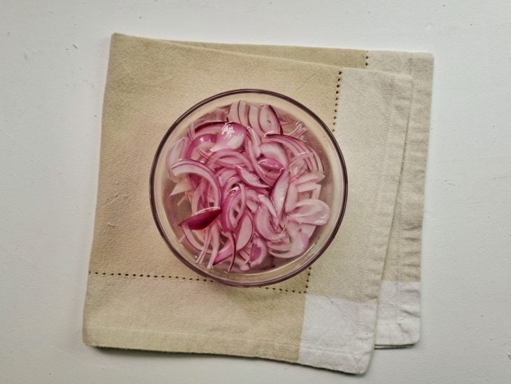 Tigela com água e cebola descascada e picada.