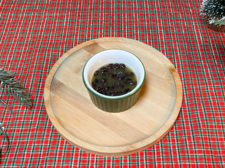 Uvas-passas hidratando no suco de laranja em potinho separado.