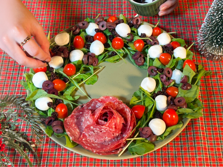 Uvas-passas escorridas, nozes e raspas cítricas finalizando a montagem da salada.