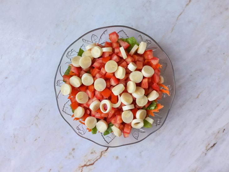 Palmito cortado em rodelas finas e distribuído uniformemente.