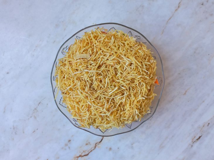 Batata palha sendo colocada por cima da salada.